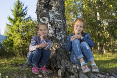 Küçük kızlar ormanda oturan