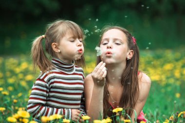 Kız kardeşler çayırlarda karahindiba tohumları saçıyor..