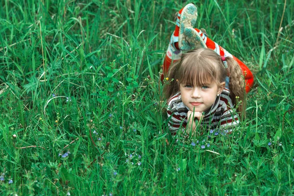 かわいいです女の子は緑の芝生に横たわっています — ストック写真