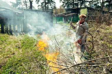Yaşlı bir kadın çiftliğinde dalları yakıyor..