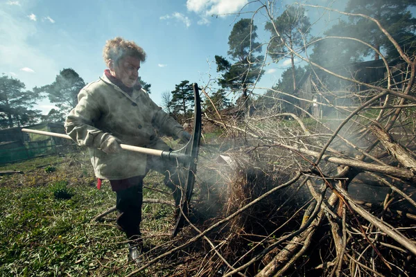 老妇人在她的农场里清扫和焚烧树枝 — 图库照片