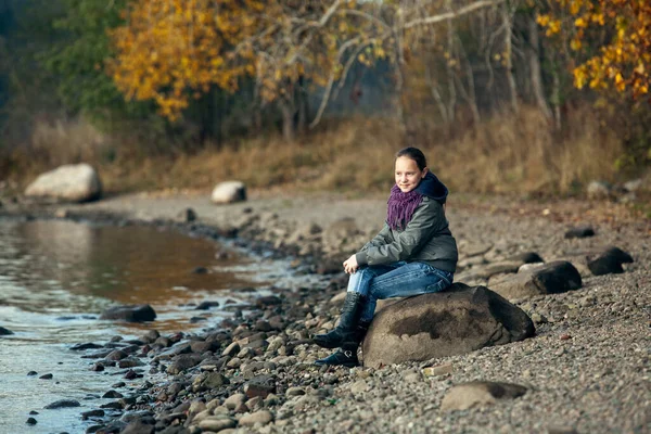 少女は川のほとりの岩の上に座っている — ストック写真