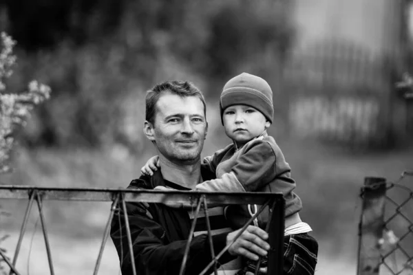 男は幼い息子を腕に抱えて屋外にいる 白黒写真 — ストック写真