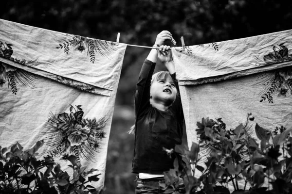 Lovely little five-year girl with clothespin outdoor. Black and white photography.