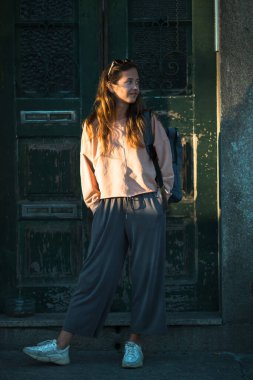 Genç bayan eski evin kapısının yanında duruyor..