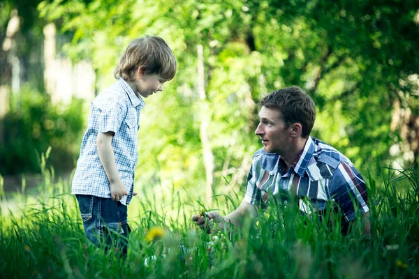 年轻的父亲和他的小儿子在绿色的公园里玩耍 — 图库照片
