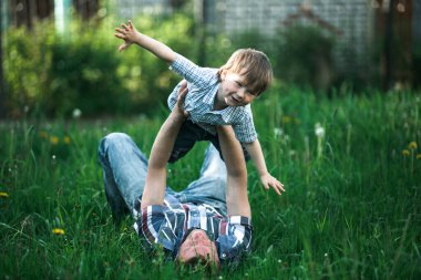 Genç baba yeşil çimlerin üzerinde oğluyla oynuyor..