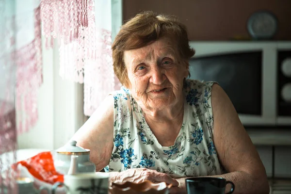 一个老年妇女坐在家里喝茶的画像 图库图片