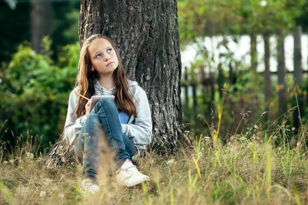 Ragazza Adolescente Che Scrive Quaderno Mentre Seduta Nel Parco Fotografia Stock