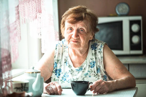 一位老年妇女养恤金领取者坐在她家的桌子旁 肖像画 — 图库照片
