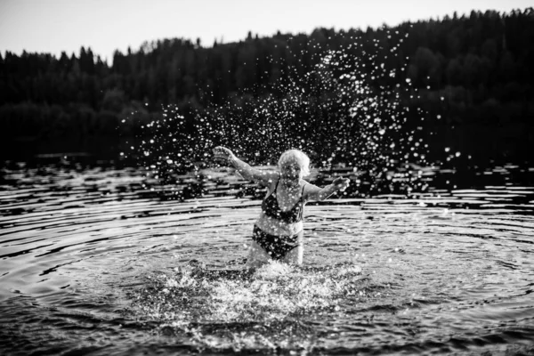 一个老年妇女在夏日落山时在河里游泳 黑白照片 — 图库照片