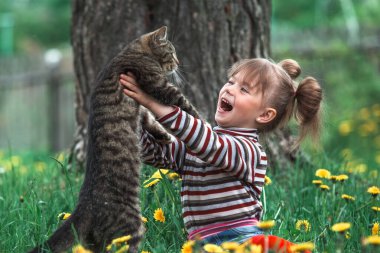 Yeşil çimlerde tatlı küçük kız ve kedi.
