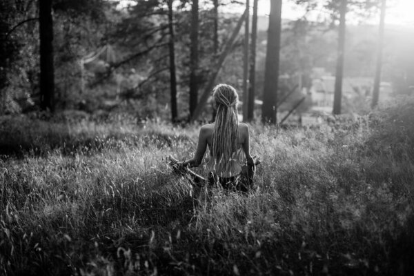 Yoga woman sit in lotos pose in the forest. Black and white photo.