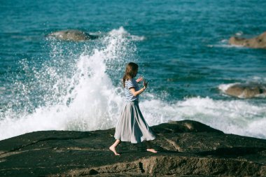 Kadın, okyanus kıyısında dans ve koreografi ile meşgul..