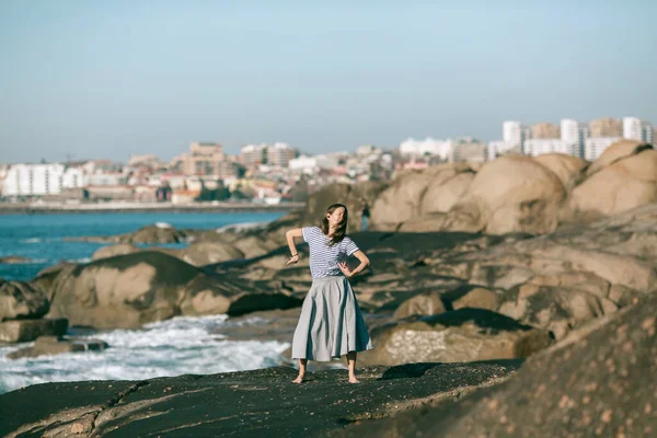 ダンサーの女性は海の岩の海岸で振付に従事している — ストック写真