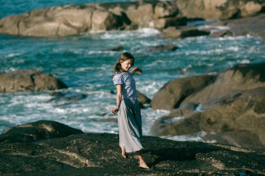 Dansçı kadın okyanus kıyısında koreografiyle meşgul..