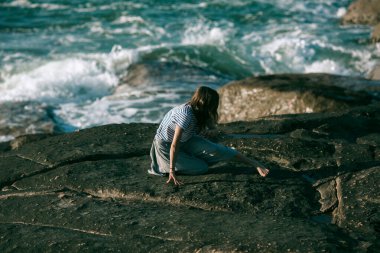 Bir kadın dansçı okyanus kıyısında koreografiyle meşgul..