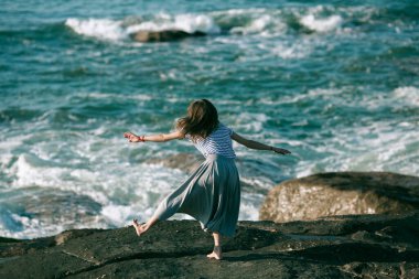 Kadın dansçı, okyanus kıyısında koreografiyle meşgul..