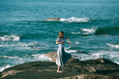 Dansçı kadın kayalık Atlantik sahillerinde koreografiyle meşgul..