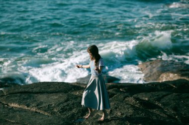 Hoş genç dansçı kadın okyanusun kayalıklarında koreografiyle meşgul..