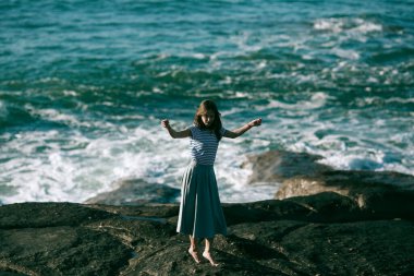 Hoş genç dansçı kadın okyanusun kayalık sahillerinde koreografiyle meşgul..
