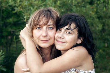 Kızın portresi mutlu annesine sarılıyor, açık havada..