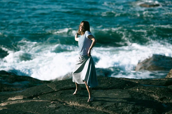 ダンサーの女性は海の岩場で振付に従事しています — ストック写真
