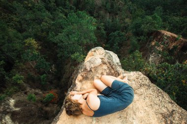 Genç kız kanyondaki kayanın tepesinde kıvrılmış yatıyor.. 