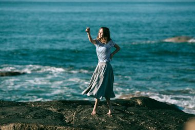 Genç bir kadın okyanus kıyısında koreografiyle meşgul..