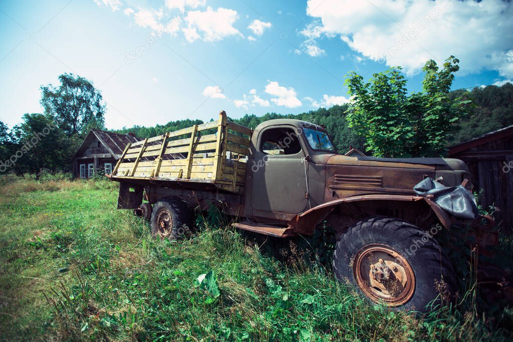 A view of an abandoned old truck in a village in the summer in northern Russia.
