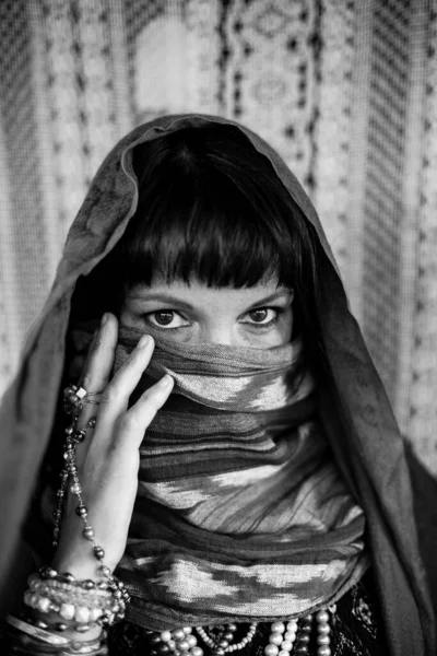 Woman covering her face with a veil. Black and white portrait.