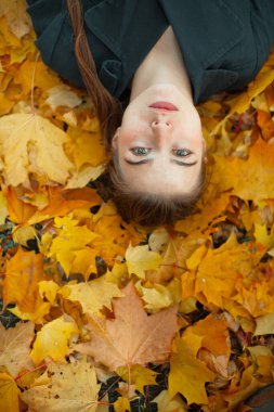Güzel kız düşen sonbahar yapraklarında yatıyor..