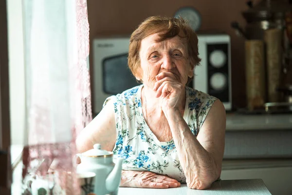 Portrait of an old retired woman sitting at a table.