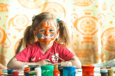 Yüz boyasıyla resim çizen küçük bir kız. Sanat terapisi..