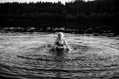 Yaşlı kadın yazın nehirde yüzüyor. Siyah beyaz fotoğraf.