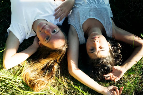 İki kız çimenlerde uzanıp eğleniyor..