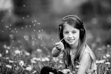 Park 'ta çimlerin üzerinde oturan küçük tatlı kız. Siyah beyaz fotoğraf.