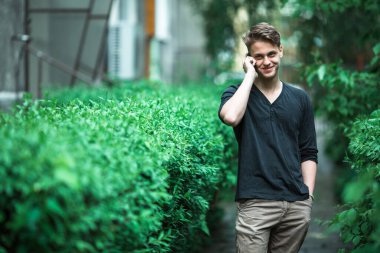 Genç adam sokakta cep telefonuyla konuşuyor..