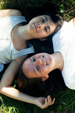 Çimlerin üzerinde uzanmış güzel vakit geçiren iki genç kızın portresi.. 
