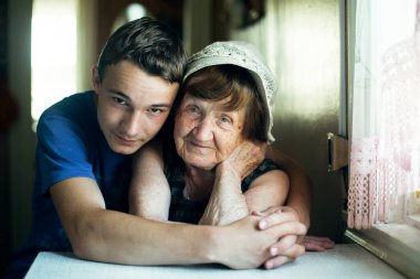 Yaşlı bir kadın ve torunu kucaklaşarak portre çekiyorlar.