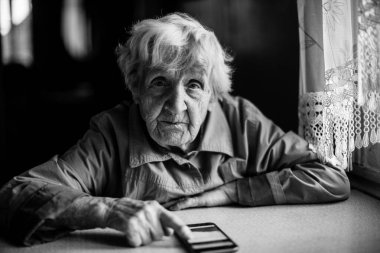Masada oturan yaşlı kadın. Siyah beyaz fotoğraf.