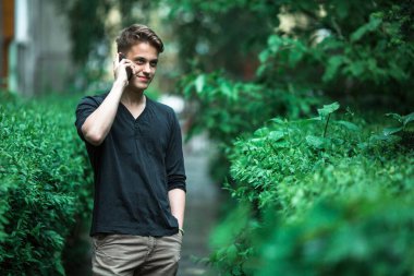 Dışarıda cep telefonuyla konuşan hoş bir genç adam..