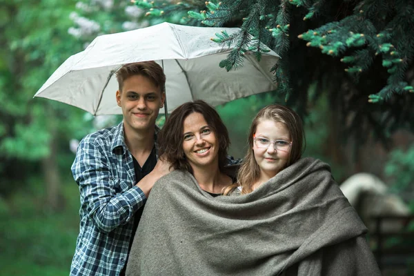 一个女人 带着她们的成年儿子和女儿在公园里的伞下 — 图库照片