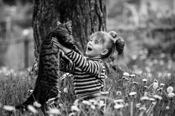 かわいい女の子が公園で猫と遊んでいます 白黒写真 — ストック写真