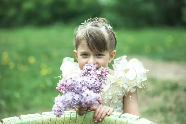 花园里有一束紫丁香的小女孩的画像 — 图库照片