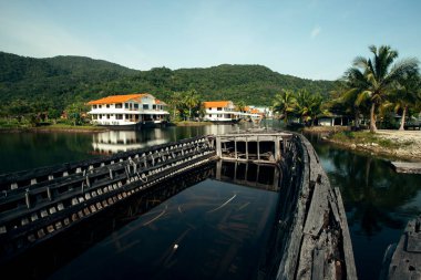 Tayland ormanında terk edilmiş eski deniz tekneleriyle göl manzarası.