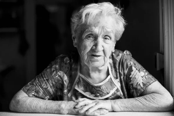 Portrait of old woman in her home. Black-and-white photo.