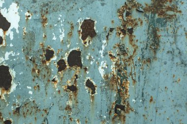 Pas ve eski boya izleriyle yıpranmış metal bir yüzey..