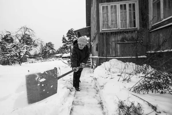 Стара Жінка Прибирає Сніг Біля Свого Сільського Будинку Чорно Біле — стокове фото