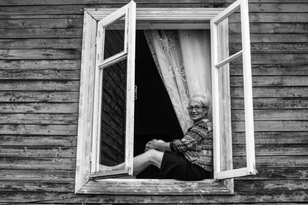 一个坐在村舍窗上的成年妇女 黑白照片 — 图库照片